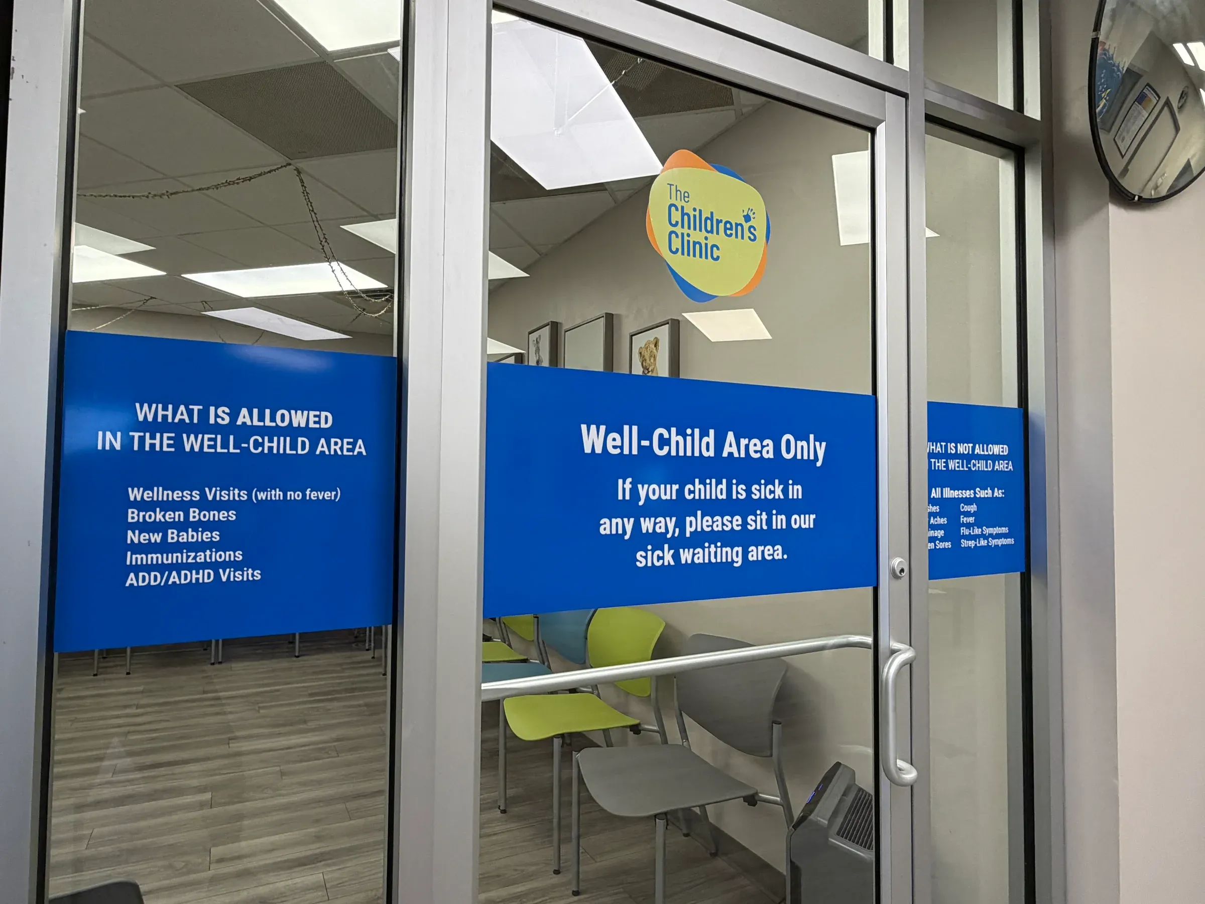 Blue vinyl on the lobby's glass doors marking the well-child waiting area, with the clinic logo above