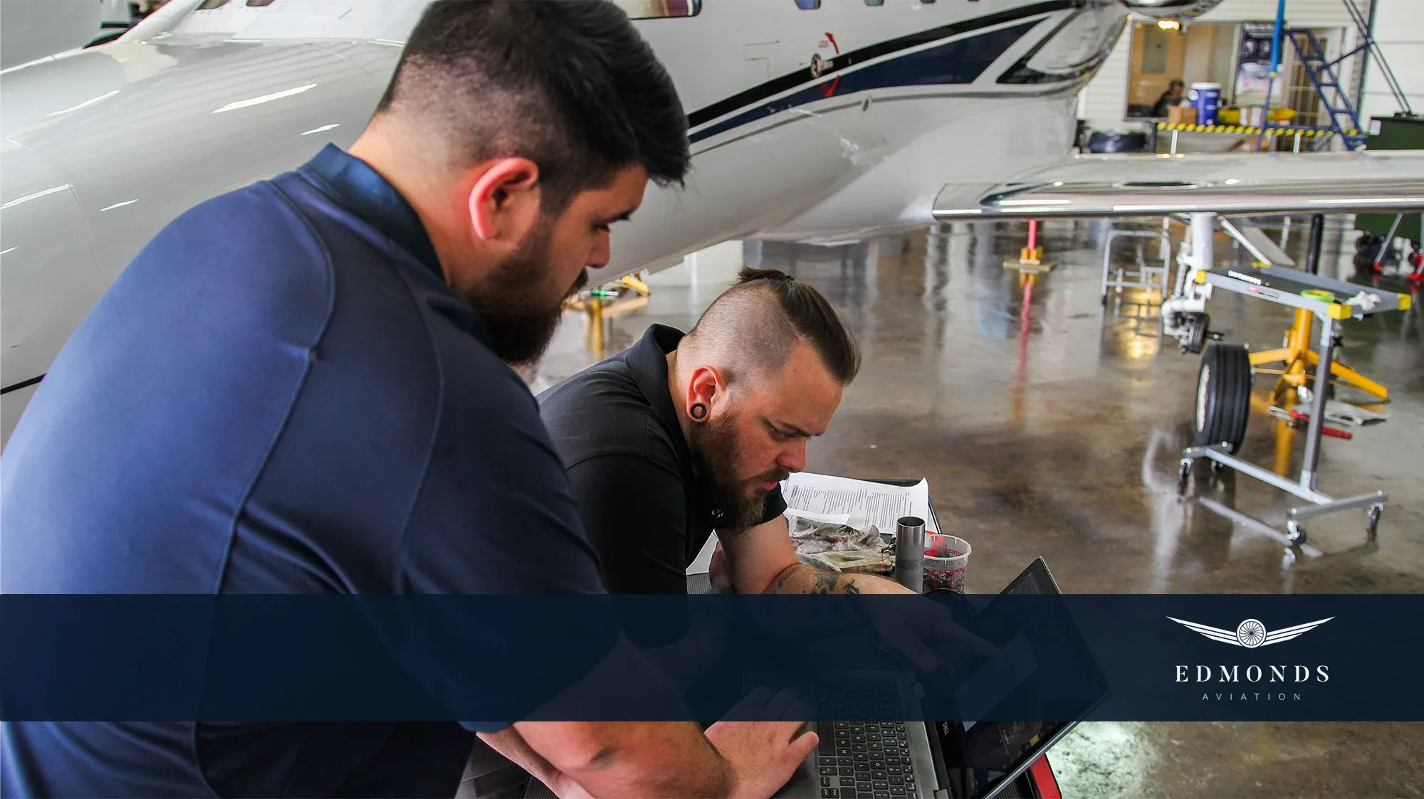 A technician working at a laptop beside an aircraft
